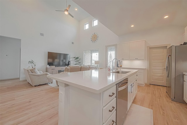 kitchen with a center island with sink, stainless steel appliances, light countertops, open floor plan, and a sink