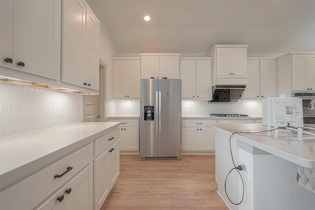 kitchen featuring light wood finished floors, white cabinets, decorative backsplash, stainless steel appliances, and light countertops