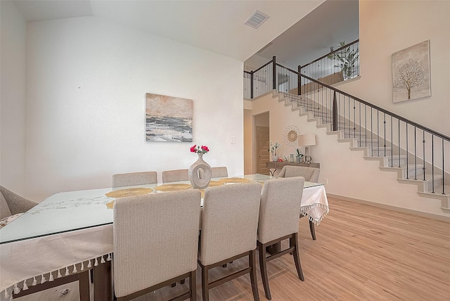 dining area with a high ceiling, stairway, wood finished floors, and visible vents