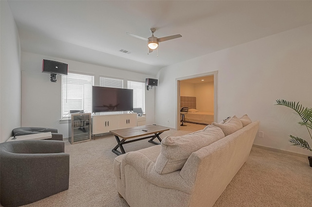 living area featuring wine cooler, light colored carpet, visible vents, ceiling fan, and baseboards