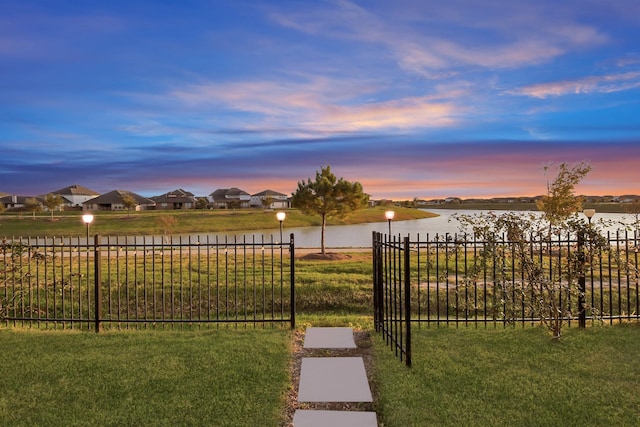 view of yard featuring a residential view, a water view, and fence