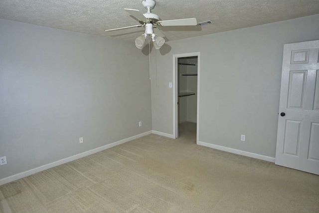 57 Sunrose Ct, Lake Jackson, TX 77566 - unfurnished bedroom featuring a textured ceiling, light colored carpet, visible vents, baseboards, and a walk in closet