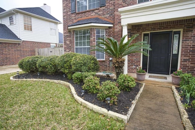 57 Sunrose Ct, Lake Jackson, TX 77566 - view of exterior entry with brick siding, a lawn, and fence