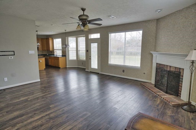 57 Sunrose Ct, Lake Jackson, TX 77566 - unfurnished living room featuring baseboards, visible vents, dark wood finished floors, a brick fireplace, and a sink