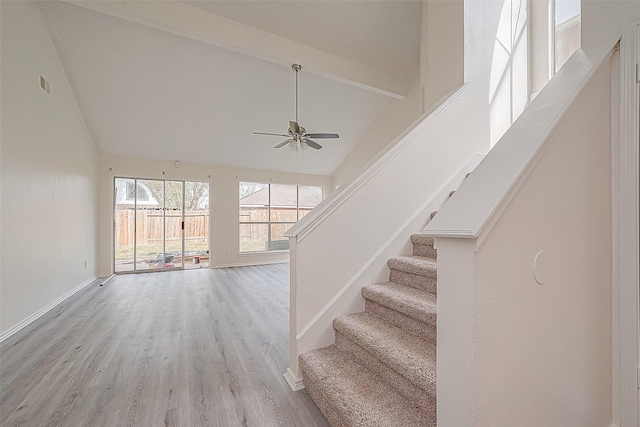 stairway with visible vents, ceiling fan, wood finished floors, high vaulted ceiling, and baseboards