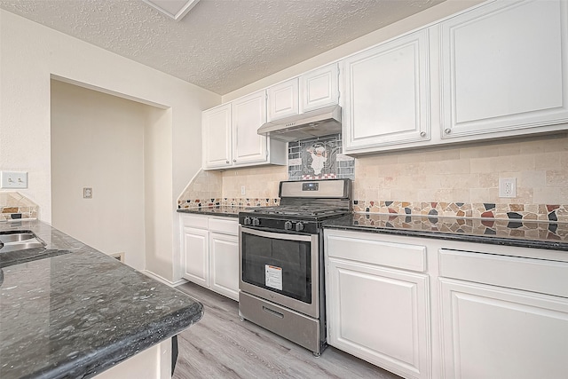 kitchen featuring gas stove, white cabinets, and under cabinet range hood