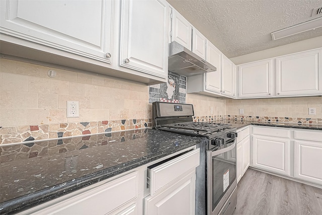 kitchen with stainless steel gas stove, under cabinet range hood, white cabinets, and dark stone countertops