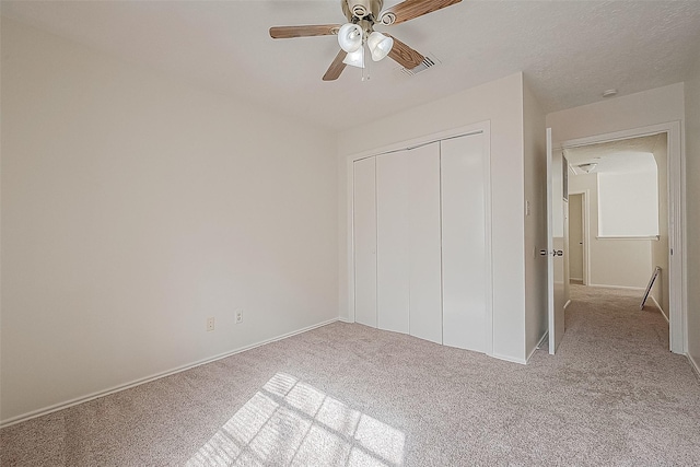 unfurnished bedroom with baseboards, visible vents, a ceiling fan, light colored carpet, and a closet