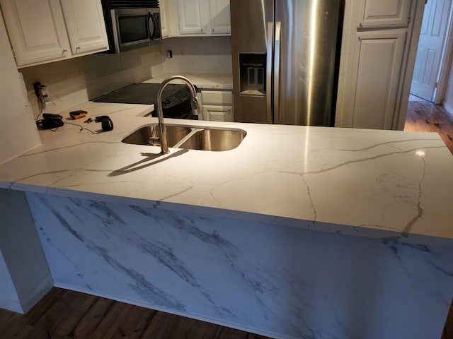 kitchen with appliances with stainless steel finishes, white cabinetry, a sink, and dark wood-style floors