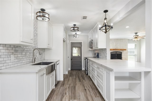 kitchen featuring light stone counters, visible vents, appliances with stainless steel finishes, white cabinetry, and a sink