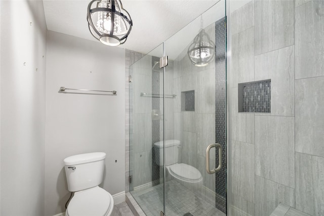 full bath featuring toilet, a stall shower, and baseboards