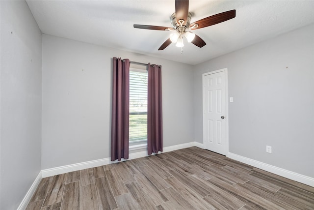 empty room featuring a ceiling fan, baseboards, and light wood finished floors