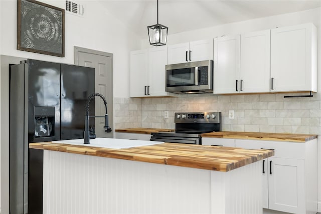 kitchen with wood counters, appliances with stainless steel finishes, white cabinets, and decorative light fixtures