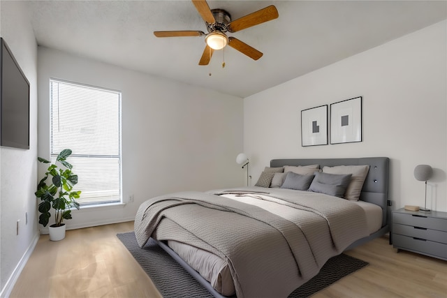 bedroom featuring light wood-style flooring, baseboards, and ceiling fan