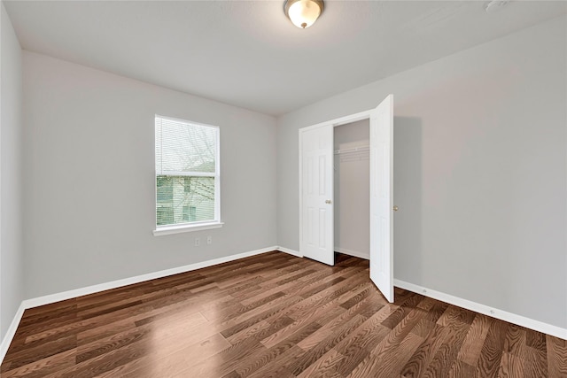 unfurnished bedroom with baseboards, dark wood finished floors, and a closet