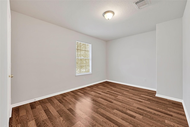 unfurnished room with baseboards, visible vents, and dark wood finished floors