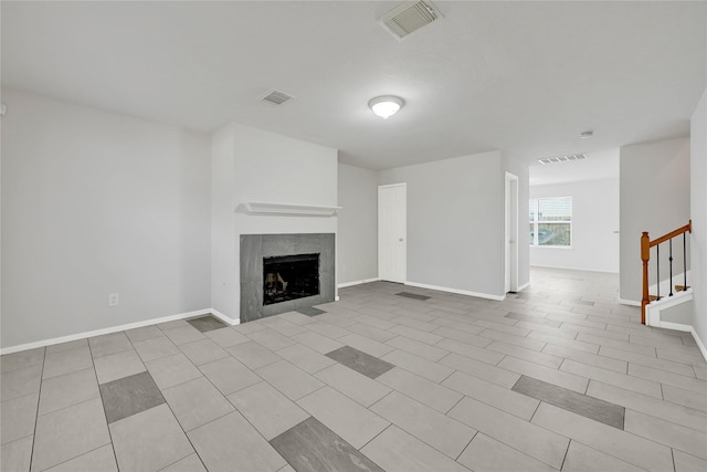 unfurnished living room featuring stairway, baseboards, visible vents, and a tile fireplace