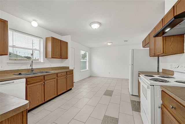 kitchen with brown cabinetry, white appliances, a sink, and extractor fan