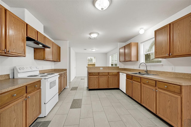 kitchen with white appliances, brown cabinets, light countertops, under cabinet range hood, and a sink