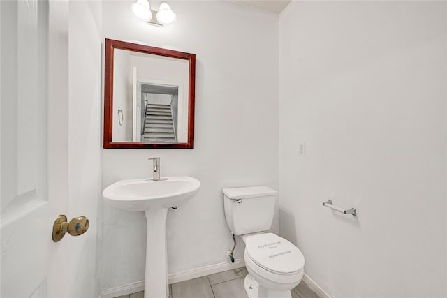 half bathroom featuring a sink, toilet, and baseboards