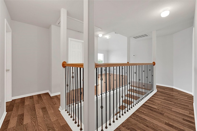 corridor featuring baseboards, visible vents, dark wood finished floors, and an upstairs landing