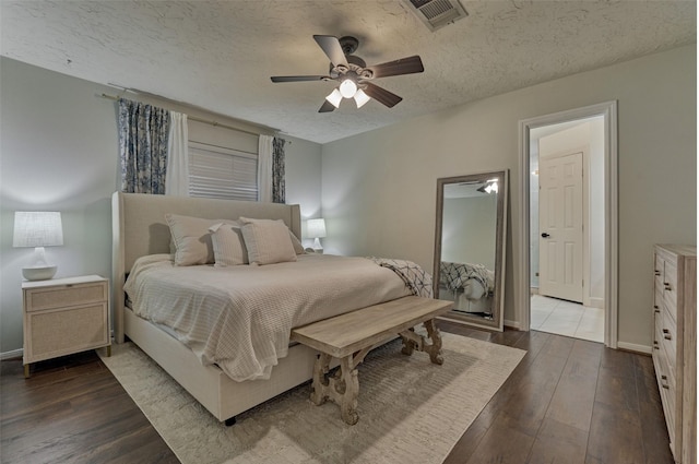 bedroom with visible vents, baseboards, a ceiling fan, dark wood-style floors, and a textured ceiling