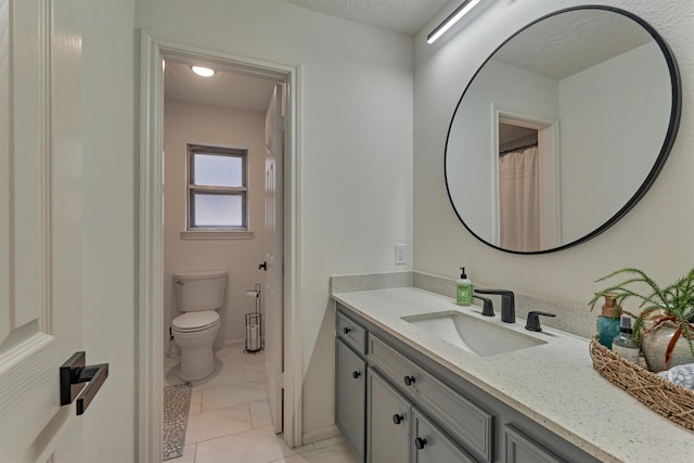 full bathroom featuring baseboards, vanity, toilet, and a textured ceiling