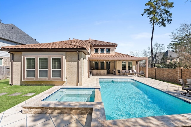 rear view of house with a fenced in pool, a patio, an in ground hot tub, a fenced backyard, and a tiled roof