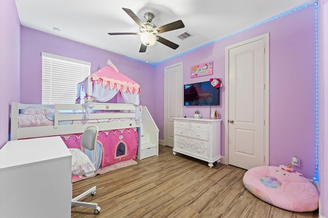 bedroom with light wood-style floors, visible vents, and ceiling fan