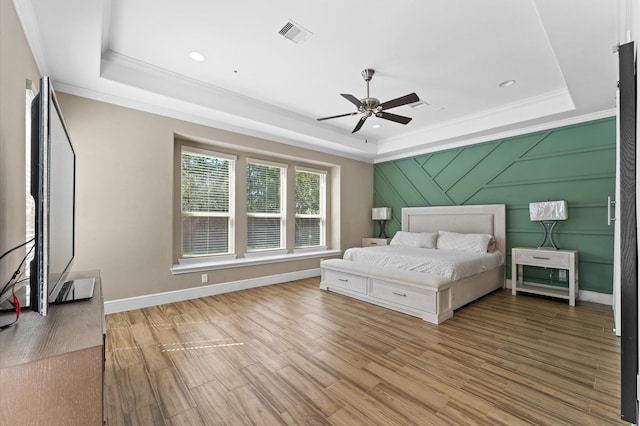 bedroom with a tray ceiling, visible vents, and wood finished floors