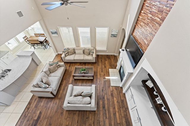 living area with visible vents, ceiling fan, a towering ceiling, and baseboards