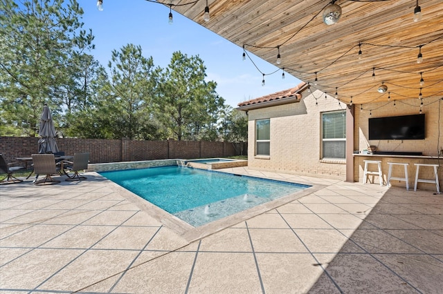 view of swimming pool with a patio area, a pool with connected hot tub, fence, and outdoor dry bar