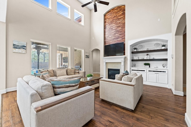 living area featuring a glass covered fireplace, a healthy amount of sunlight, and dark wood finished floors