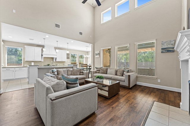 living room with a fireplace, wood finished floors, a ceiling fan, visible vents, and baseboards