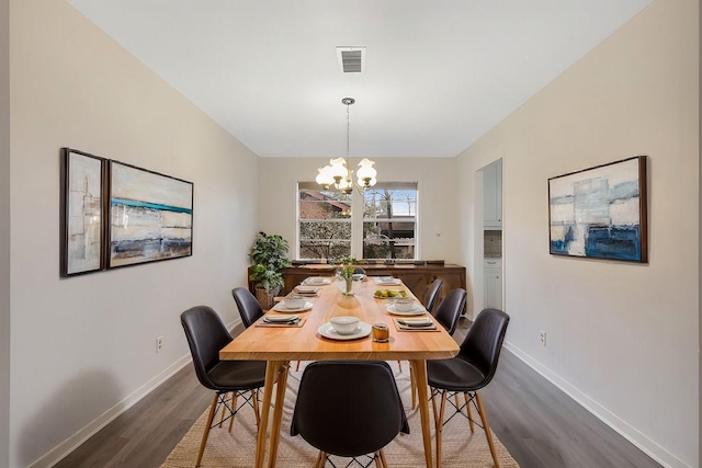 dining room featuring a chandelier, visible vents, baseboards, and wood finished floors