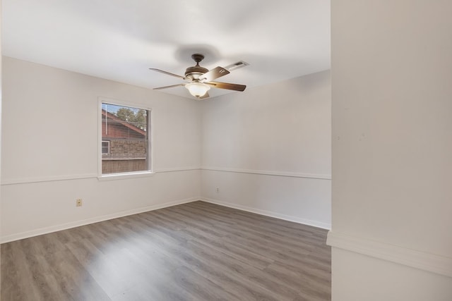 empty room featuring visible vents, wood finished floors, a ceiling fan, and baseboards