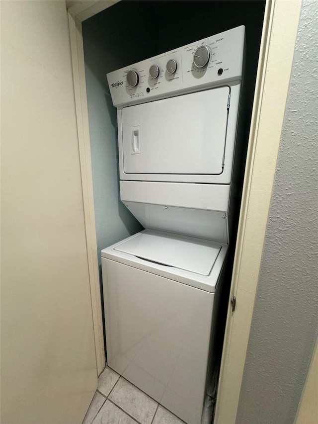 laundry room with stacked washing maching and dryer, light tile patterned floors, and laundry area