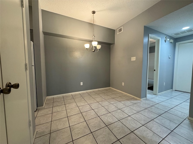 empty room featuring a textured ceiling, a chandelier, visible vents, and baseboards