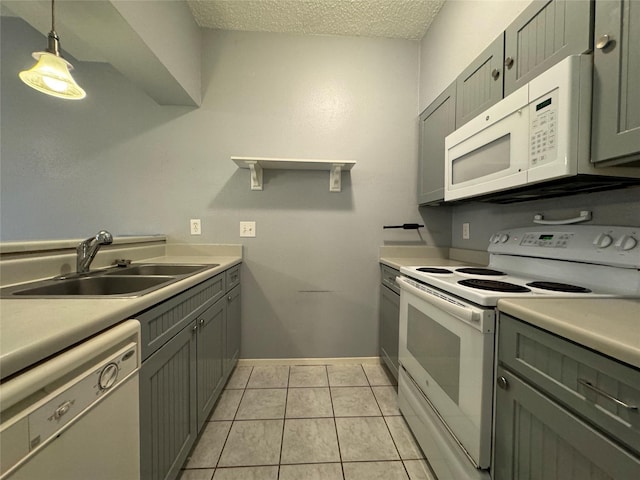 kitchen with a textured ceiling, white appliances, a sink, light countertops, and hanging light fixtures