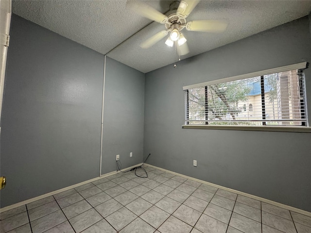 empty room with ceiling fan, a textured ceiling, and light tile patterned flooring