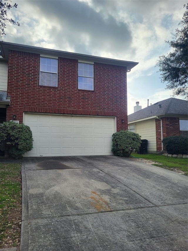 view of front facade with a garage, driveway, and brick siding