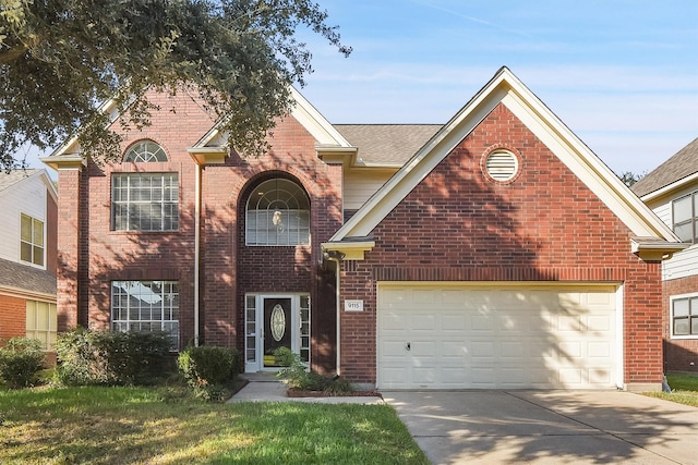 traditional home featuring an attached garage, a front lawn, concrete driveway, and brick siding