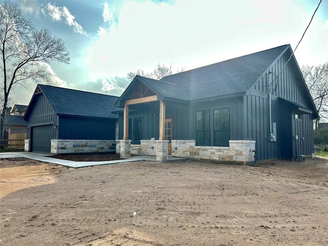 modern inspired farmhouse featuring board and batten siding, stone siding, and a shingled roof