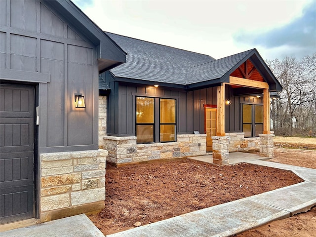 view of front of home featuring stone siding, board and batten siding, and roof with shingles