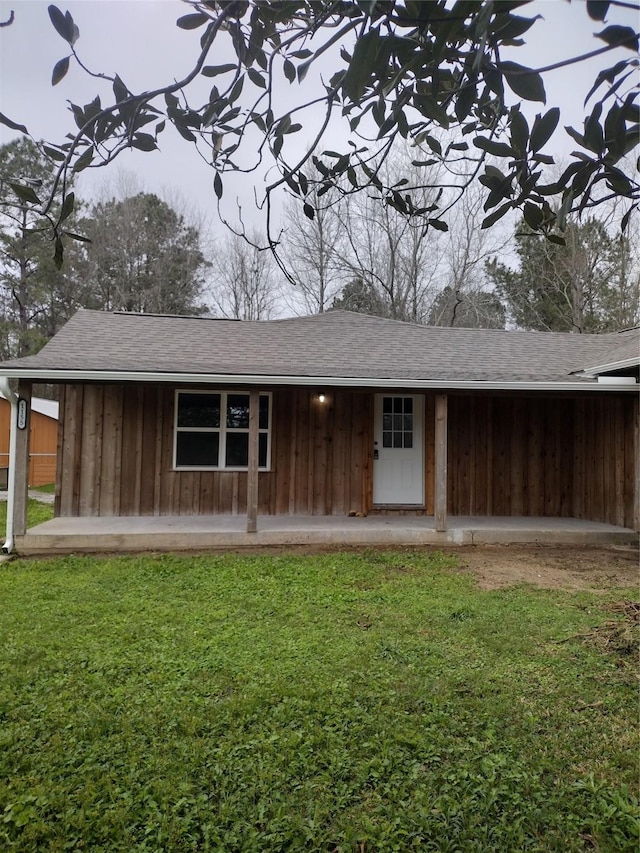 exterior space with board and batten siding, a front yard, and roof with shingles