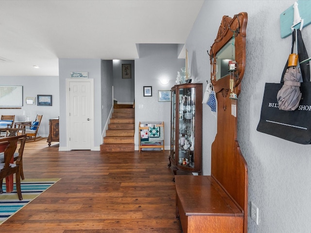 interior space with dark wood-type flooring, baseboards, and stairs