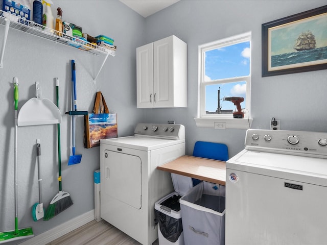 laundry area featuring cabinet space, light wood-style flooring, baseboards, and separate washer and dryer