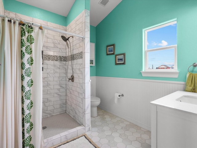 full bathroom featuring a wainscoted wall, visible vents, toilet, a stall shower, and vanity