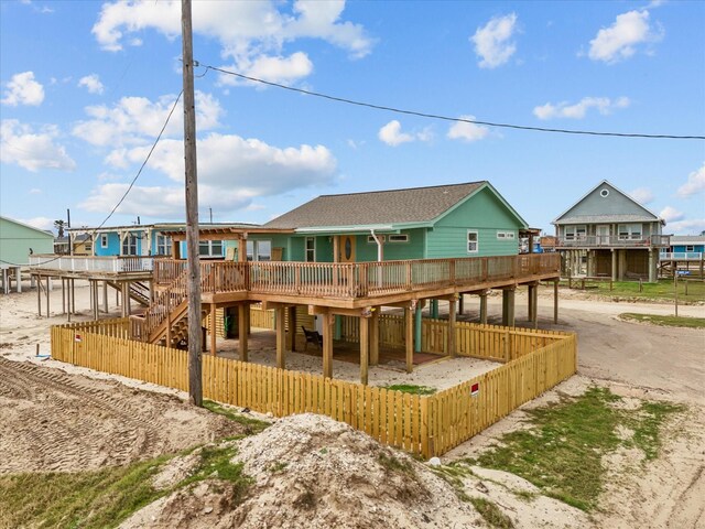 1103 White Cap Dr, Surfside Beach, TX 77541 - back of property with a wooden deck, dirt driveway, and stairway