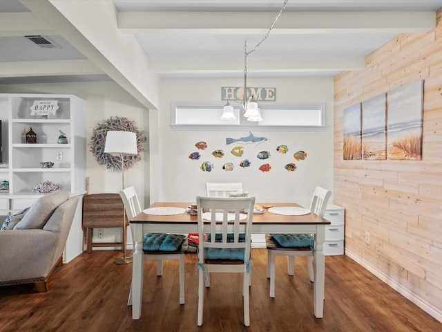 dining room featuring wooden walls, a notable chandelier, visible vents, beam ceiling, and dark wood-style floors